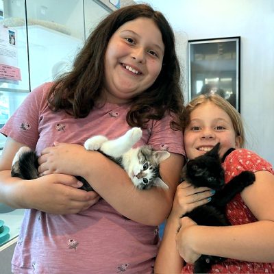 Two children holding kittens and smiling